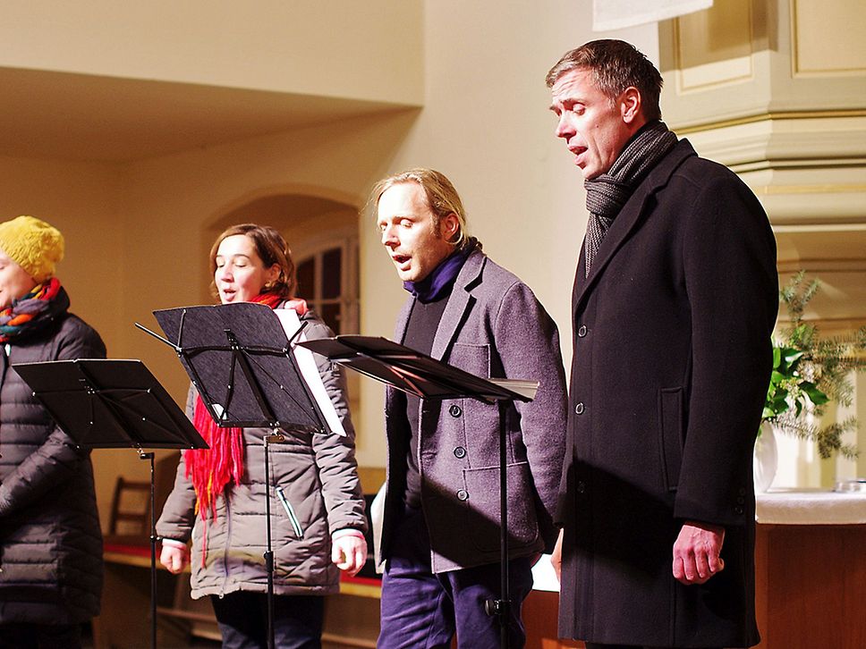 Zwei Frauen und zwei Männer singen im Chor, vor ihnen stehen Notenständer.